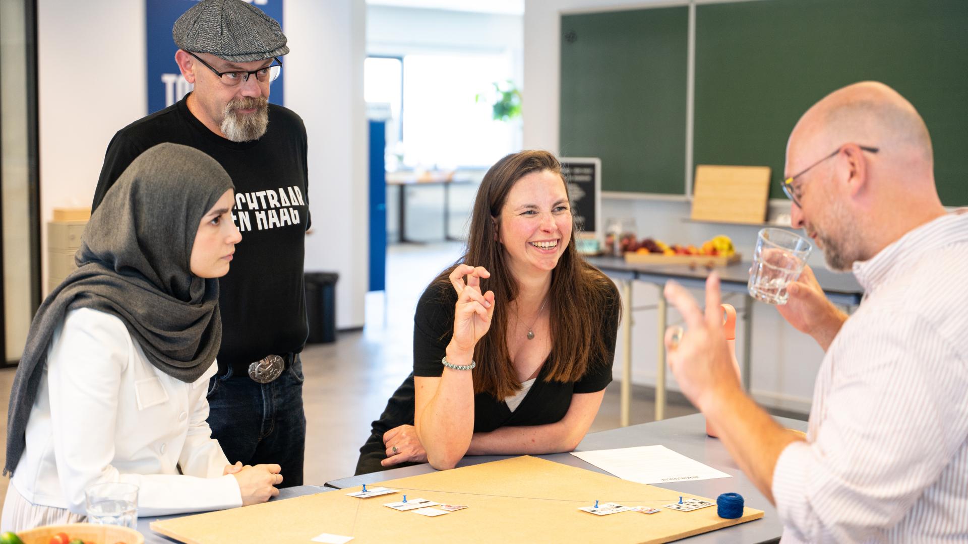 Vier mensen rond kaartjes aan tafel